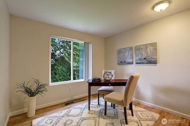 office featuring light wood-type flooring, visible vents, and baseboards