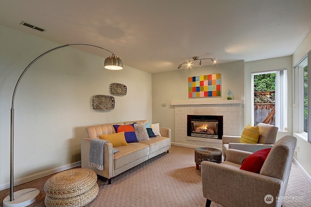 living room with carpet floors, a fireplace, visible vents, track lighting, and baseboards