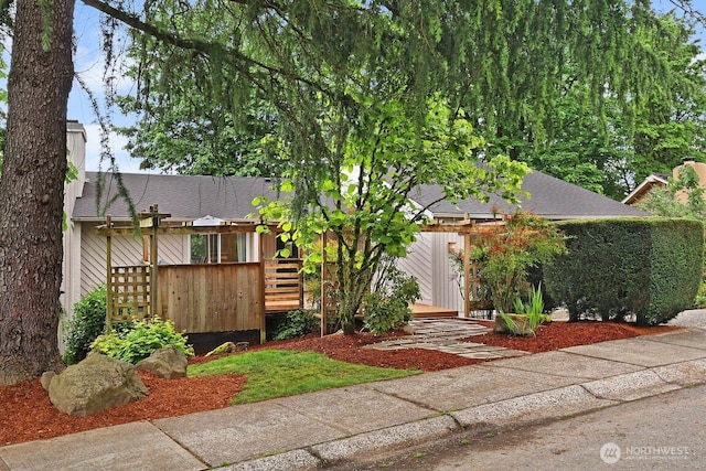 view of front of property with a deck and roof with shingles