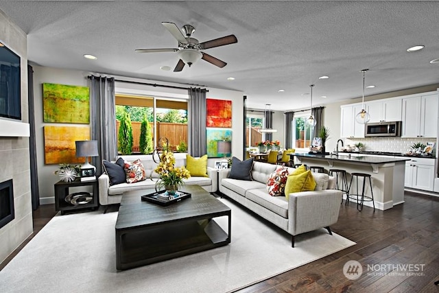 living room featuring dark hardwood / wood-style flooring, a healthy amount of sunlight, a textured ceiling, and a fireplace