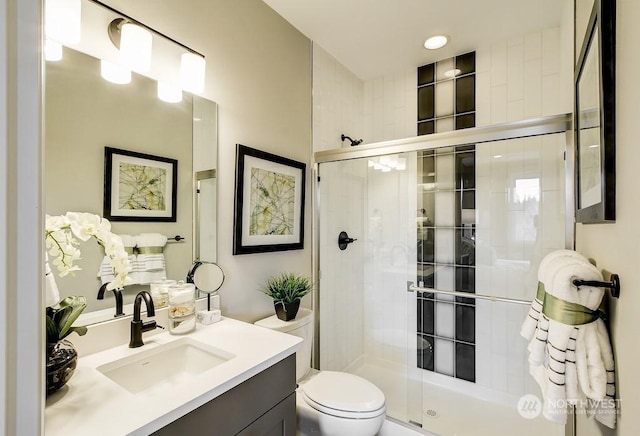 bathroom featuring vanity, toilet, and a shower with shower door