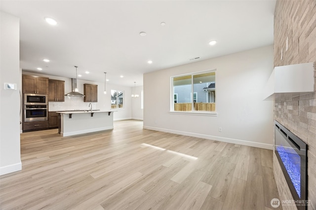 unfurnished living room with sink, light hardwood / wood-style floors, and a large fireplace