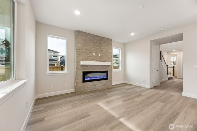 unfurnished living room with plenty of natural light, a fireplace, and light wood-type flooring