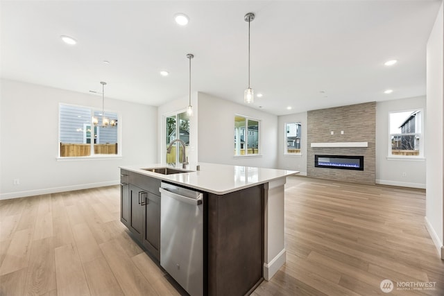 kitchen with pendant lighting, sink, dishwasher, light hardwood / wood-style floors, and a center island with sink