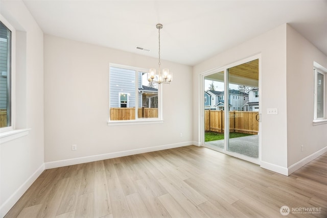 unfurnished dining area with a chandelier and light hardwood / wood-style floors