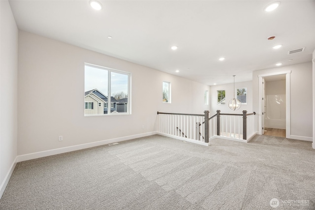 carpeted spare room with a chandelier