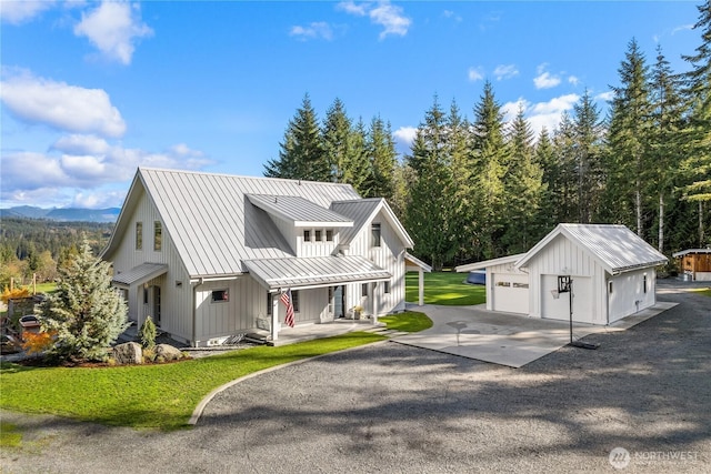 modern farmhouse style home with an outbuilding, a garage, a front yard, and covered porch