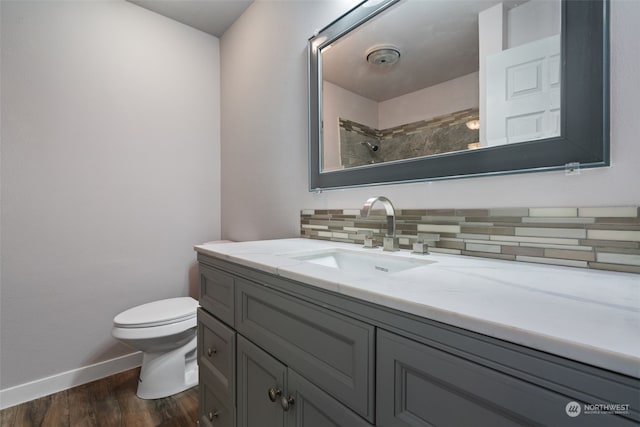 bathroom with tasteful backsplash, wood-type flooring, vanity, walk in shower, and toilet