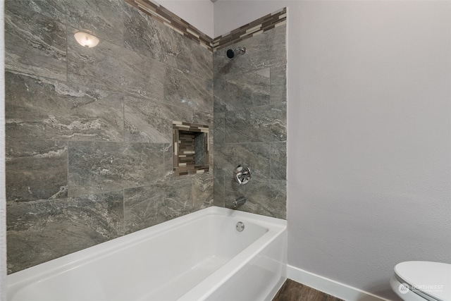 bathroom featuring tiled shower / bath, wood-type flooring, and toilet