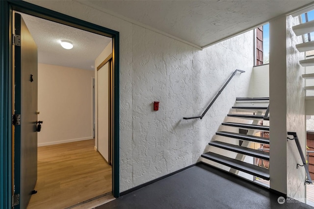 staircase with hardwood / wood-style floors and a textured ceiling