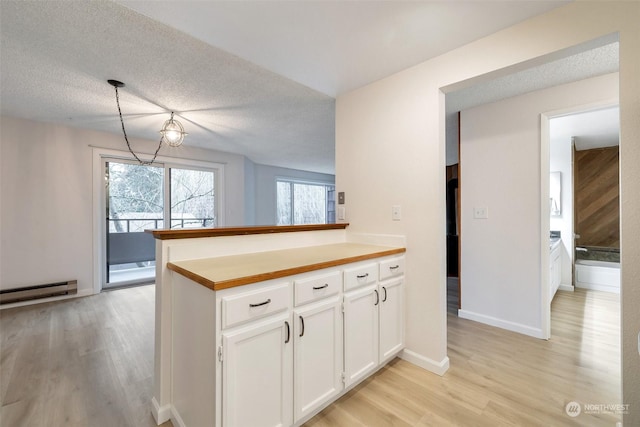 kitchen with baseboard heating, light hardwood / wood-style floors, white cabinets, decorative light fixtures, and kitchen peninsula