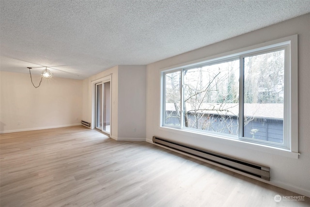 unfurnished room with a baseboard heating unit, a textured ceiling, and light hardwood / wood-style floors