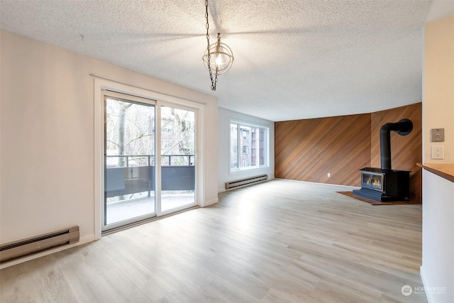 unfurnished living room featuring a baseboard radiator, wooden walls, and light wood-type flooring