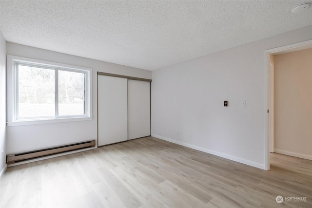 unfurnished bedroom with a baseboard heating unit, a closet, a textured ceiling, and light wood-type flooring