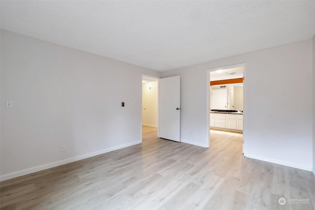 spare room with light hardwood / wood-style flooring and a textured ceiling