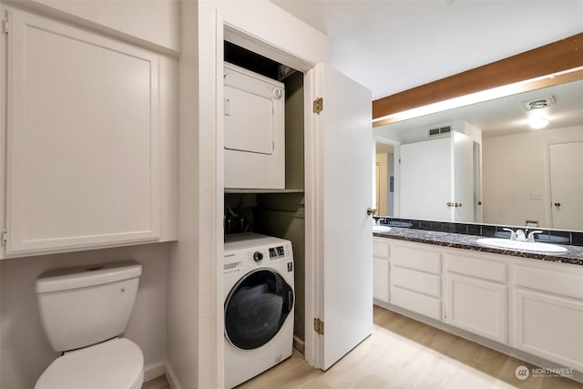 bathroom featuring vanity, hardwood / wood-style floors, toilet, and stacked washing maching and dryer