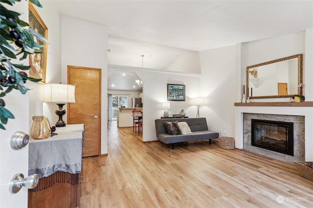 living room with a fireplace, light hardwood / wood-style flooring, and vaulted ceiling