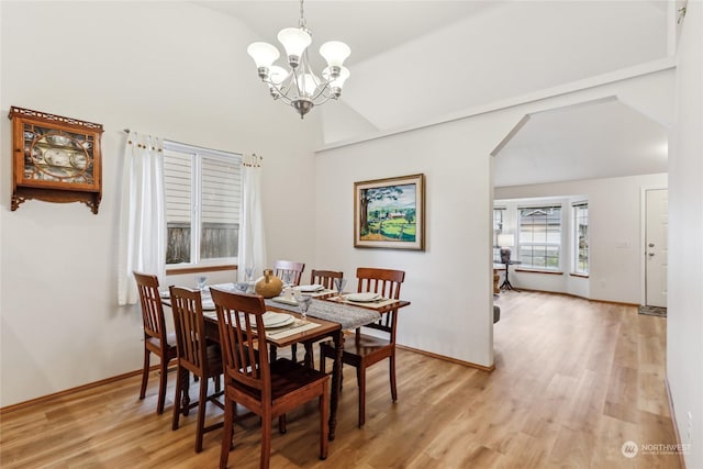 dining space with a notable chandelier, light hardwood / wood-style floors, and high vaulted ceiling