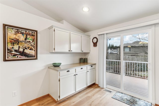 interior space featuring lofted ceiling, light hardwood / wood-style flooring, and white cabinets