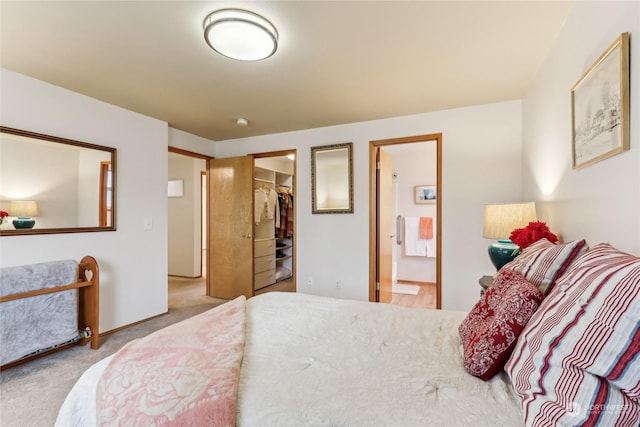 bedroom with ensuite bath, a spacious closet, a closet, and light carpet