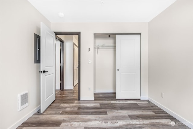 unfurnished bedroom with dark wood-type flooring, electric panel, and a closet