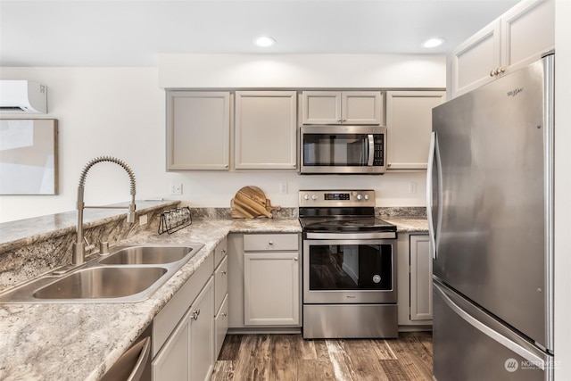 kitchen with sink, stainless steel appliances, light stone countertops, dark hardwood / wood-style flooring, and an AC wall unit