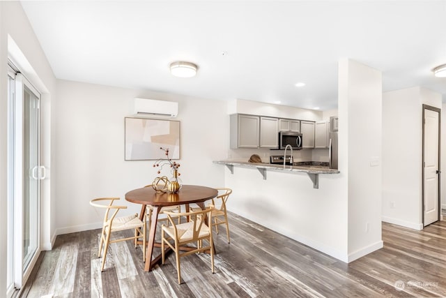 dining area with dark wood-type flooring, sink, and a wall unit AC