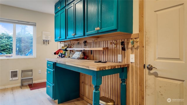 bar featuring heating unit, butcher block countertops, blue cabinetry, and light wood-type flooring