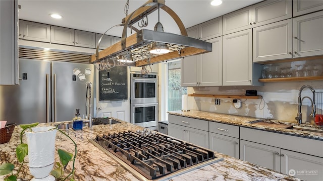 kitchen with sink, decorative light fixtures, appliances with stainless steel finishes, gray cabinets, and light stone countertops