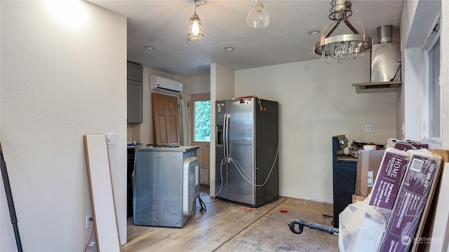 interior space with stainless steel refrigerator with ice dispenser, decorative light fixtures, a wall mounted AC, and gray cabinetry