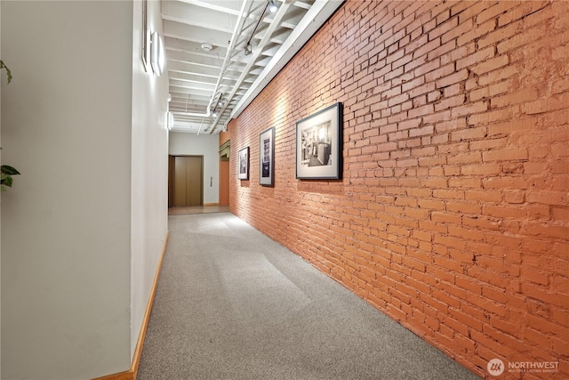 corridor featuring carpet and brick wall