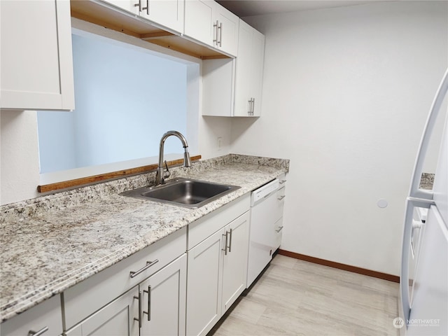 kitchen with sink, light stone counters, light wood-type flooring, white appliances, and white cabinets