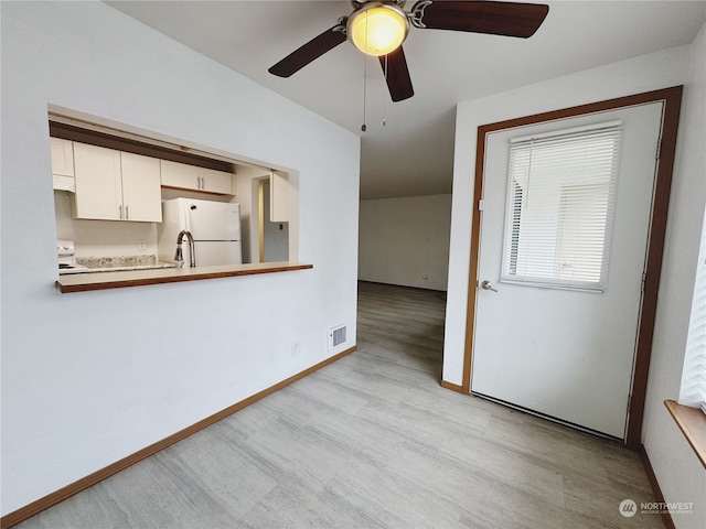 kitchen with white cabinets, white refrigerator, ceiling fan, kitchen peninsula, and light wood-type flooring