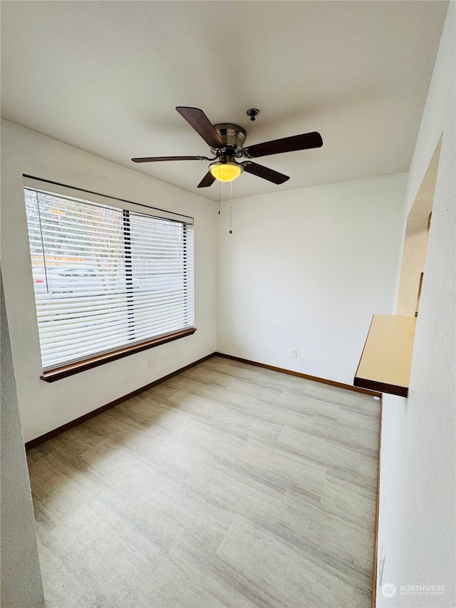 empty room with light wood-type flooring, a wealth of natural light, and ceiling fan