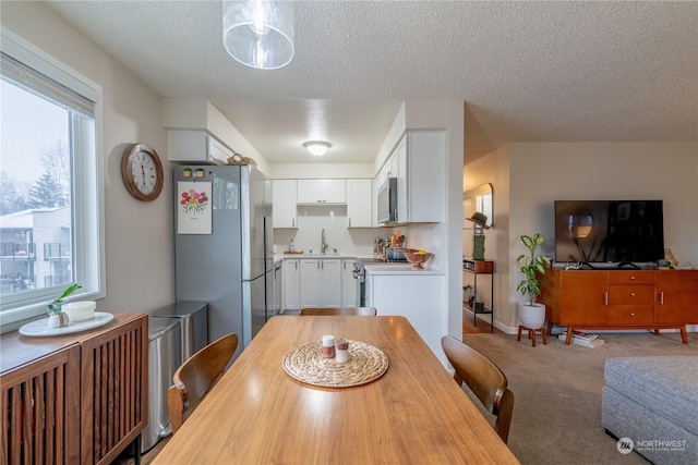 carpeted dining space featuring a sink and a textured ceiling