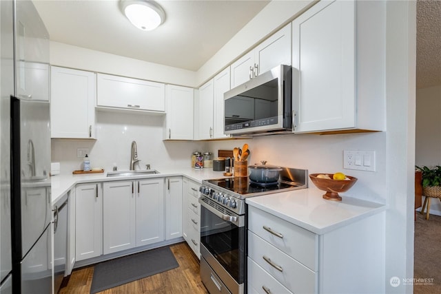 kitchen with white cabinets, stainless steel appliances, a sink, and light countertops