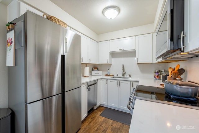 kitchen featuring stainless steel appliances, dark wood-style flooring, a sink, white cabinets, and light countertops