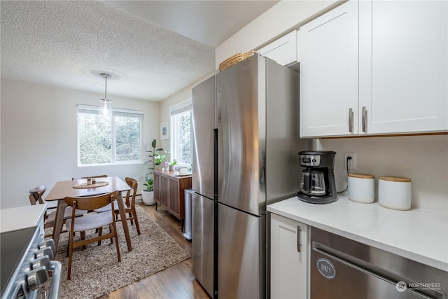 kitchen with light wood finished floors, appliances with stainless steel finishes, white cabinets, and light countertops