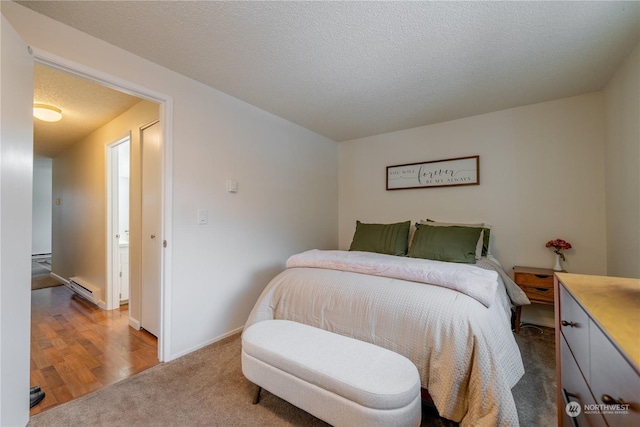 carpeted bedroom with baseboards, baseboard heating, and a textured ceiling