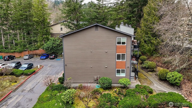 view of side of home featuring a chimney, uncovered parking, and fence