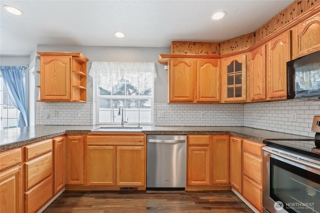 kitchen featuring dark wood finished floors, dark countertops, stainless steel appliances, open shelves, and a sink