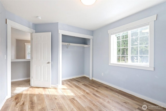 unfurnished bedroom featuring hardwood / wood-style floors, a closet, and baseboards