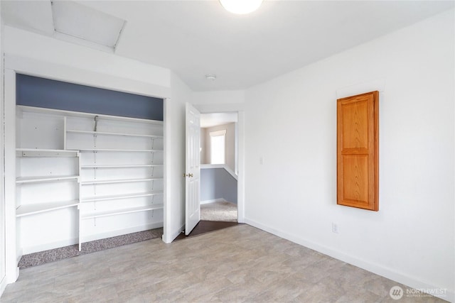 unfurnished bedroom featuring attic access, a closet, and baseboards