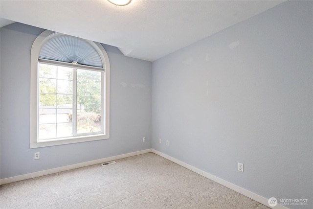 carpeted spare room with baseboards and visible vents