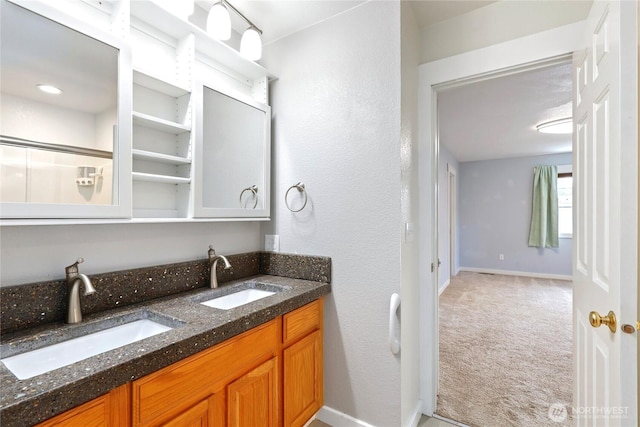 full bath featuring double vanity, a sink, and baseboards