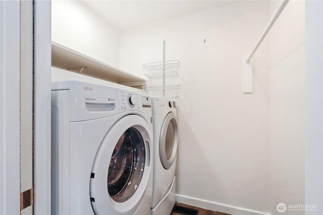 washroom with baseboards, laundry area, and washer and dryer