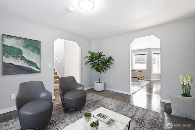 sitting room with arched walkways, wood finished floors, and baseboards