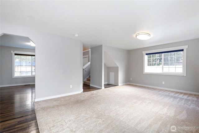 interior space with stairs, arched walkways, wood finished floors, and baseboards