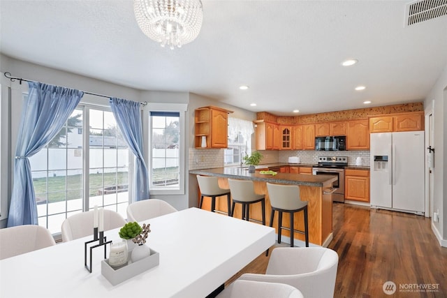 dining area featuring dark wood-style floors, recessed lighting, visible vents, and an inviting chandelier