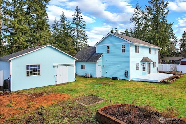 back of house with a shingled roof, fence, and a yard